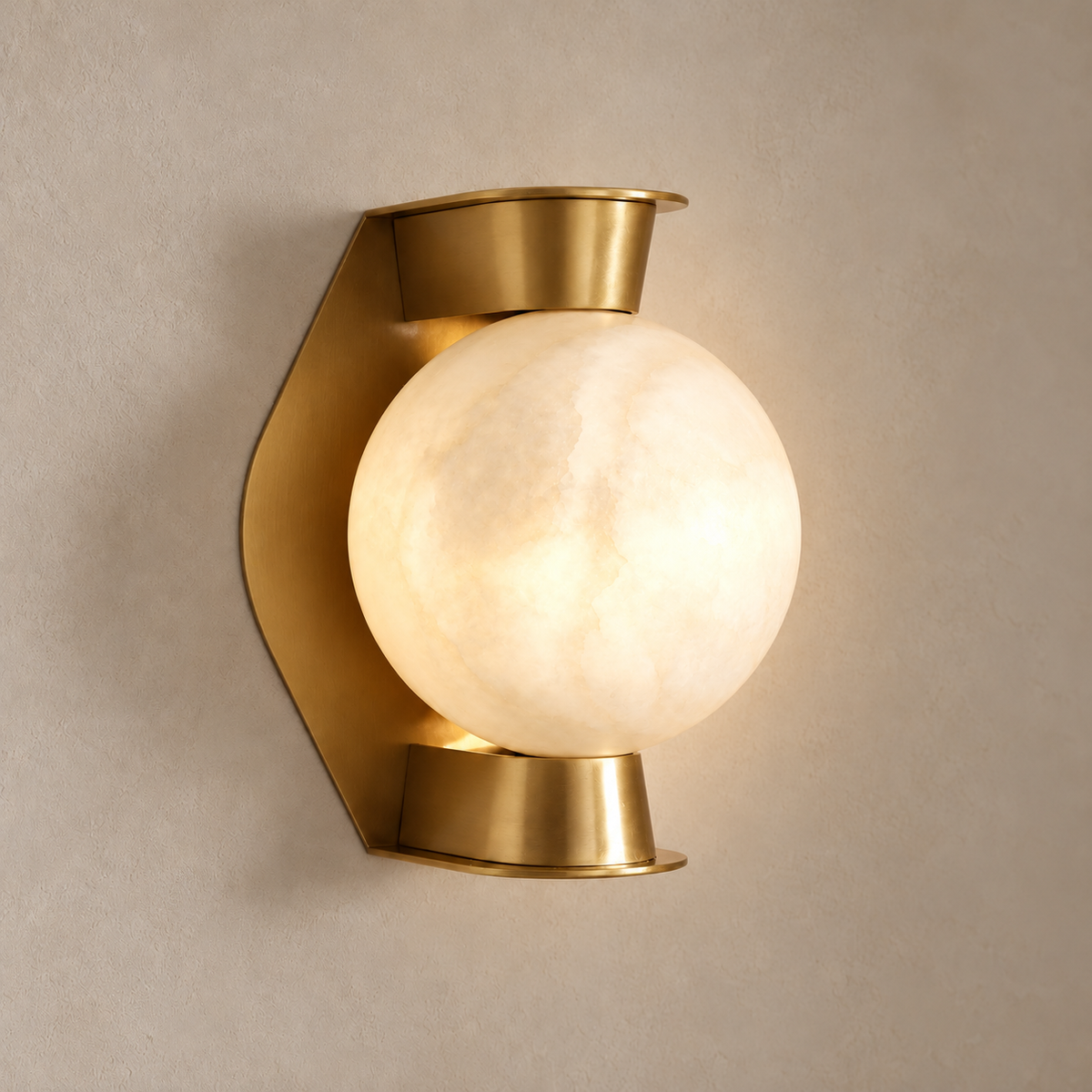 Alabaster globe and brass wall sconce, illuminated on a stone-beige wall