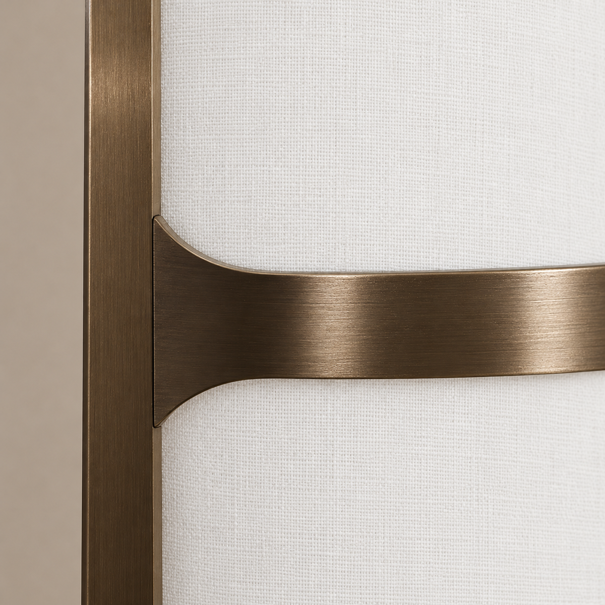Close view of the Atelier lamp’s brushed metal crossbar and curved joint against the white linen shade.