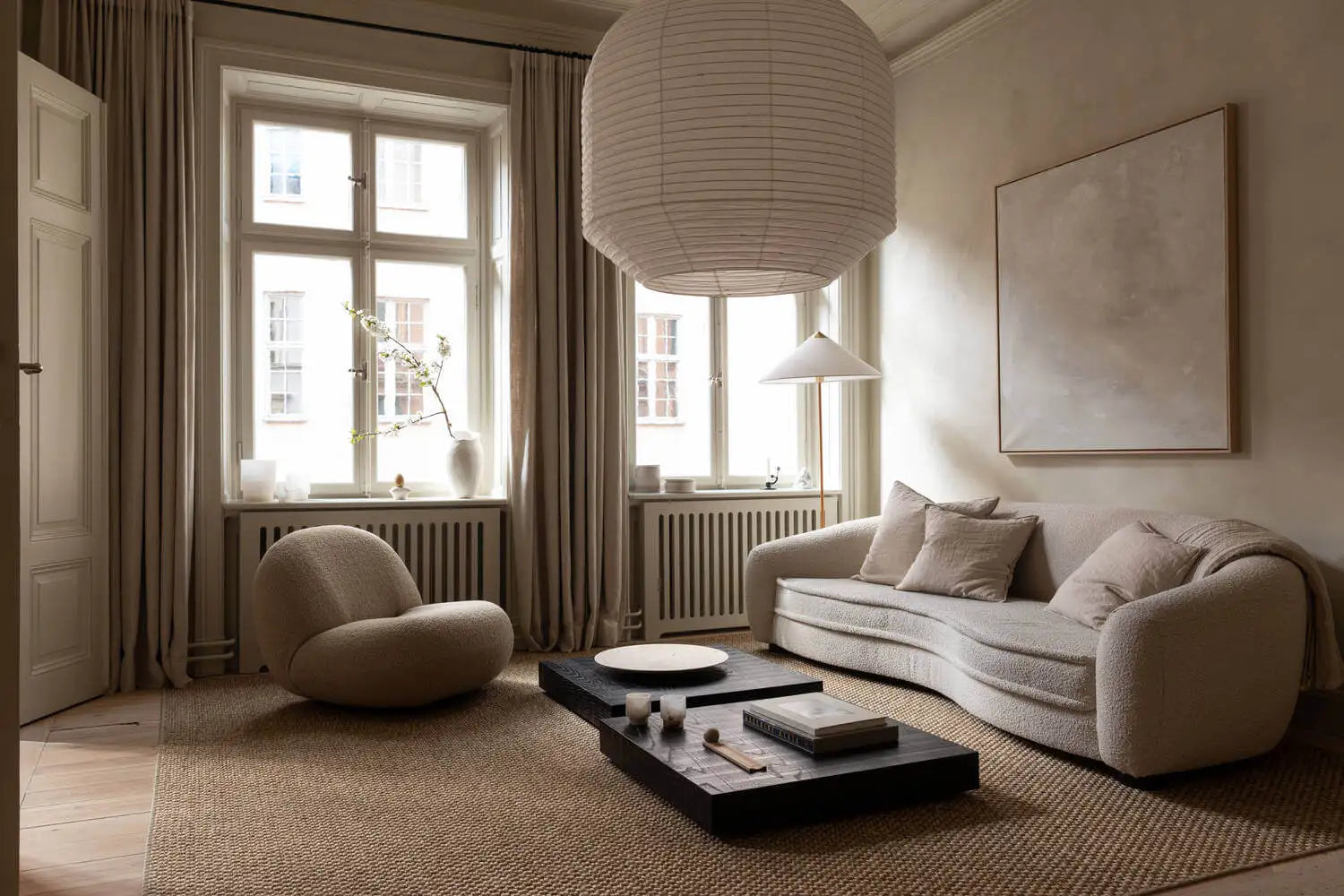 A beige, plush curved sofa with soft cushions and a modern minimalist design.