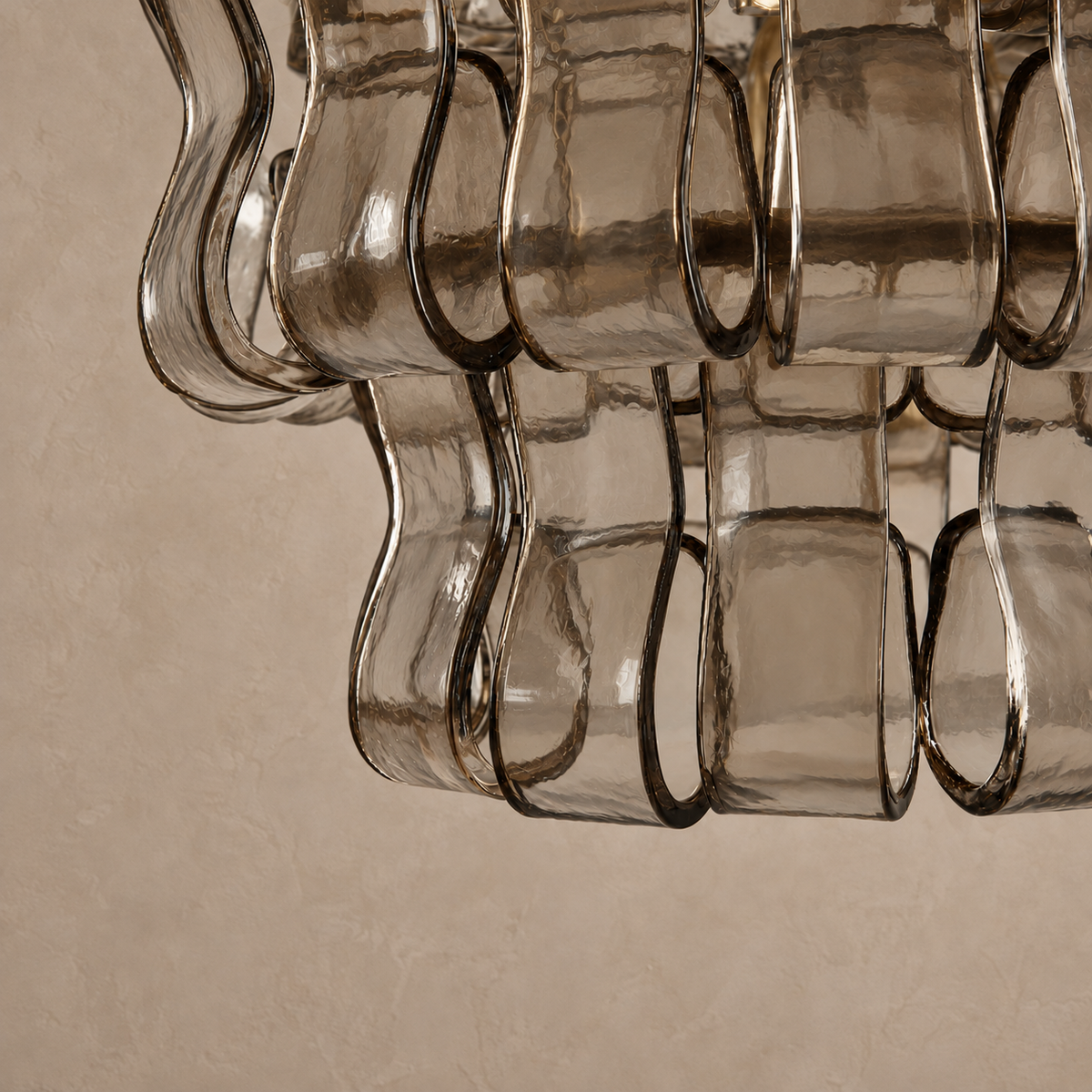 Close-up of the Bellatrix pendant’s transparent smoky brown glass, curved edges and brass supports.