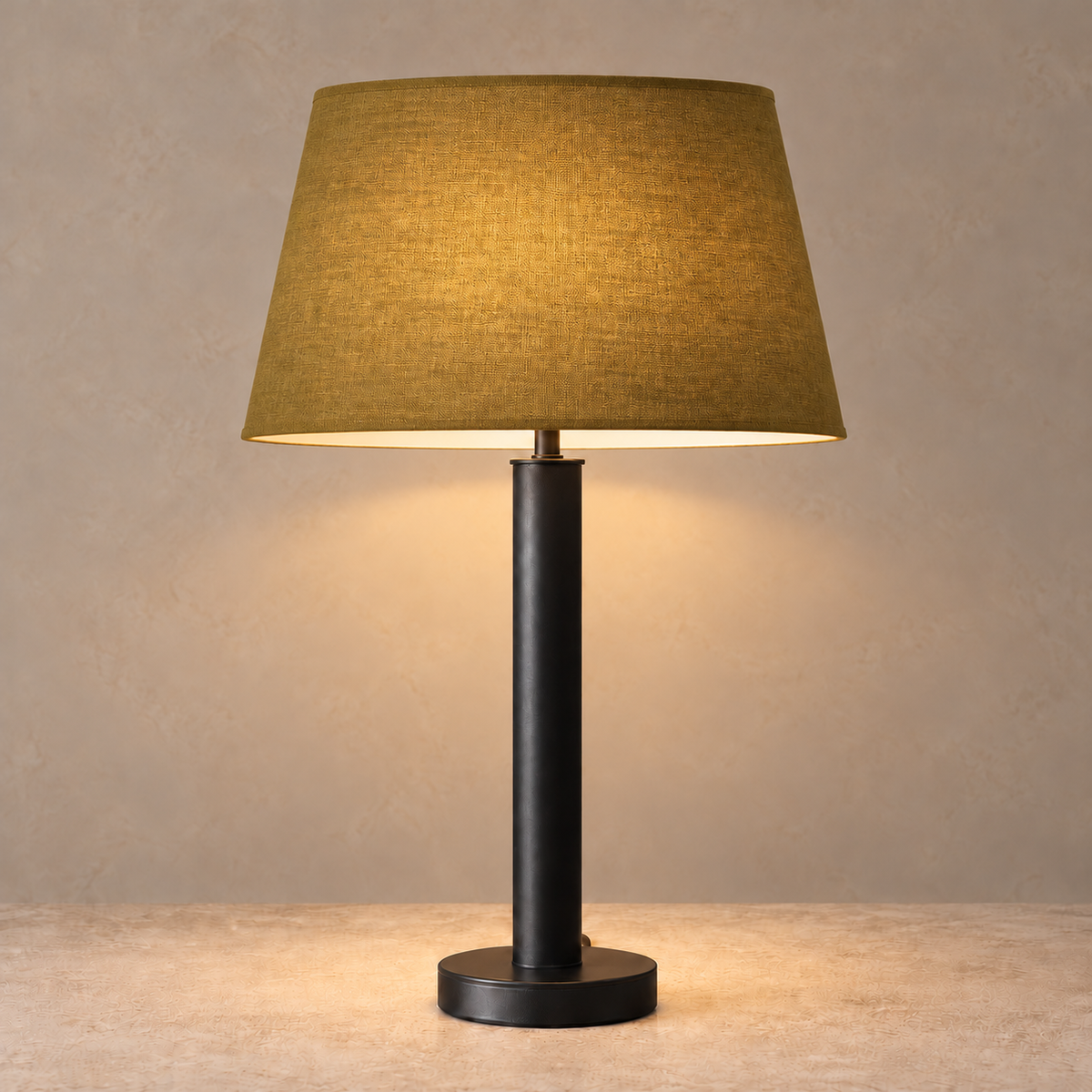 Matte black stainless steel table lamp illuminated beneath its olive tapered fabric shade.