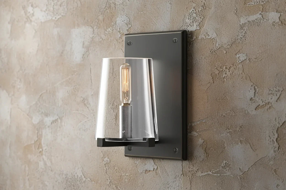 Clear glass wall sconce in a black frame, unlit on grey plaster