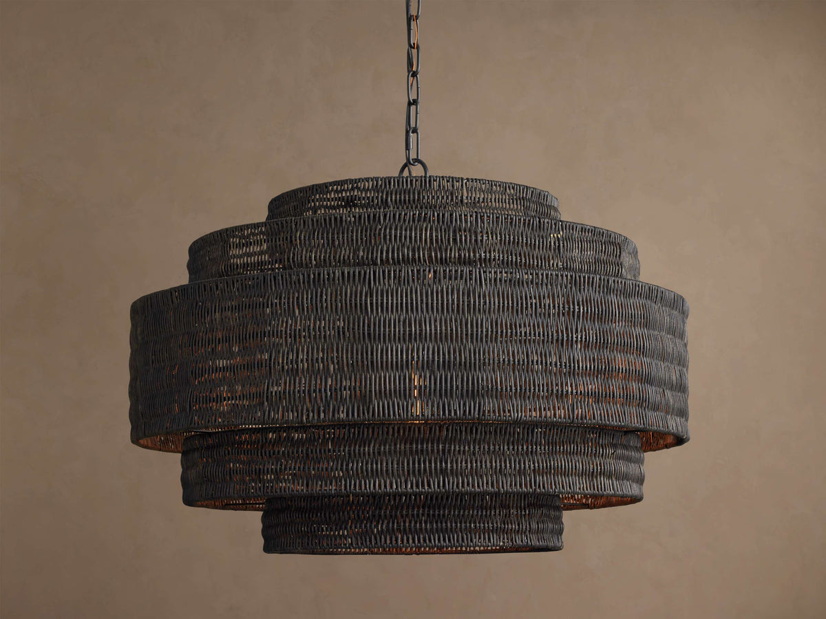 Black rattan chandelier lit, warm light showing through the woven tiers