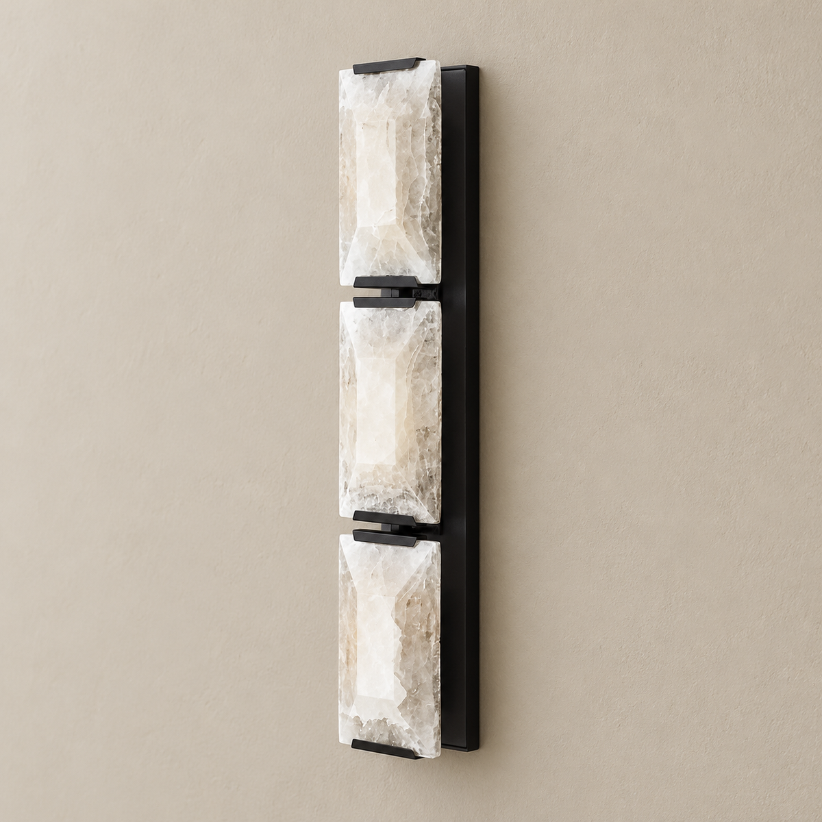 Triple calcite wall sconce with black hardware, switched off on a beige wall.