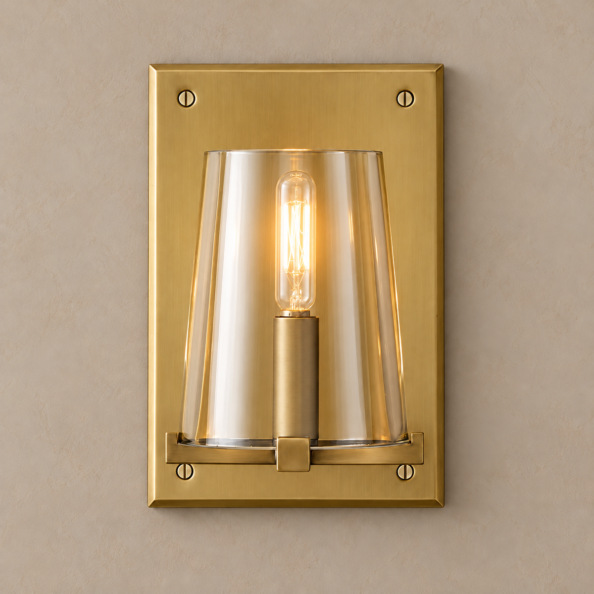 Brass and clear glass wall sconce lit, the tubular filament bulb glowing inside the shade.