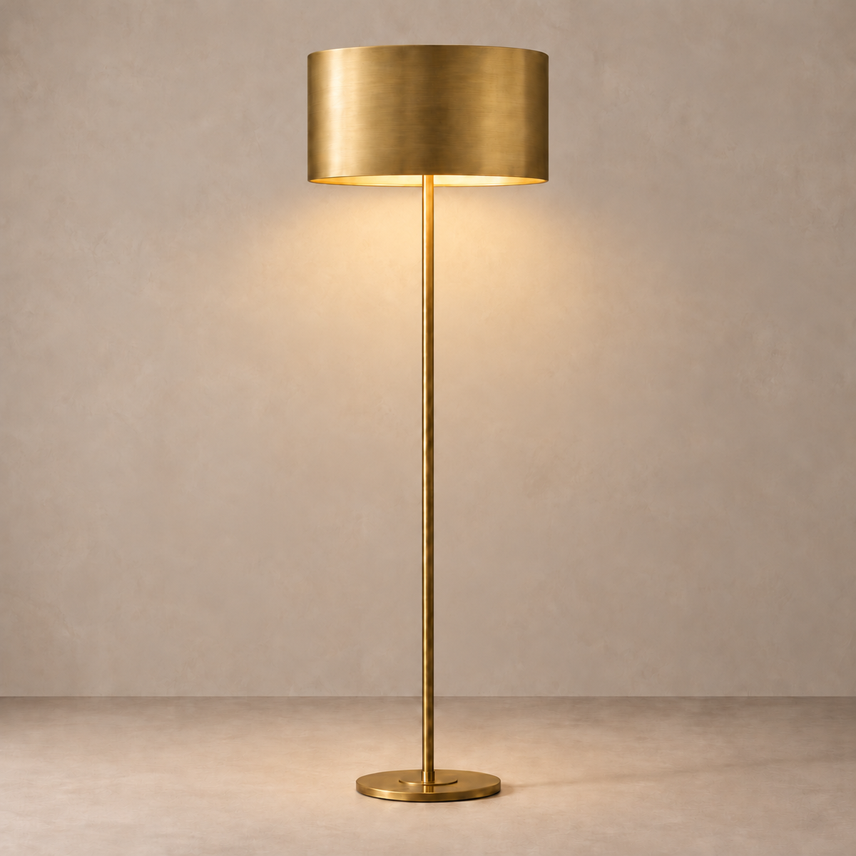 Brushed brass floor lamp illuminated beneath its opaque 50 cm metal drum shade.