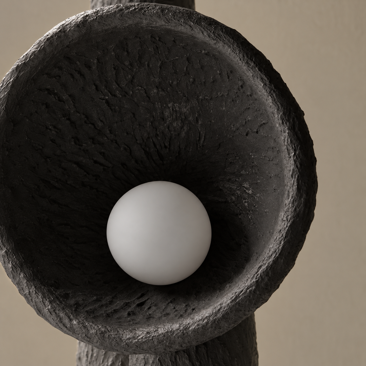 Close view of the rough black plaster bowl and white globe bulb.
