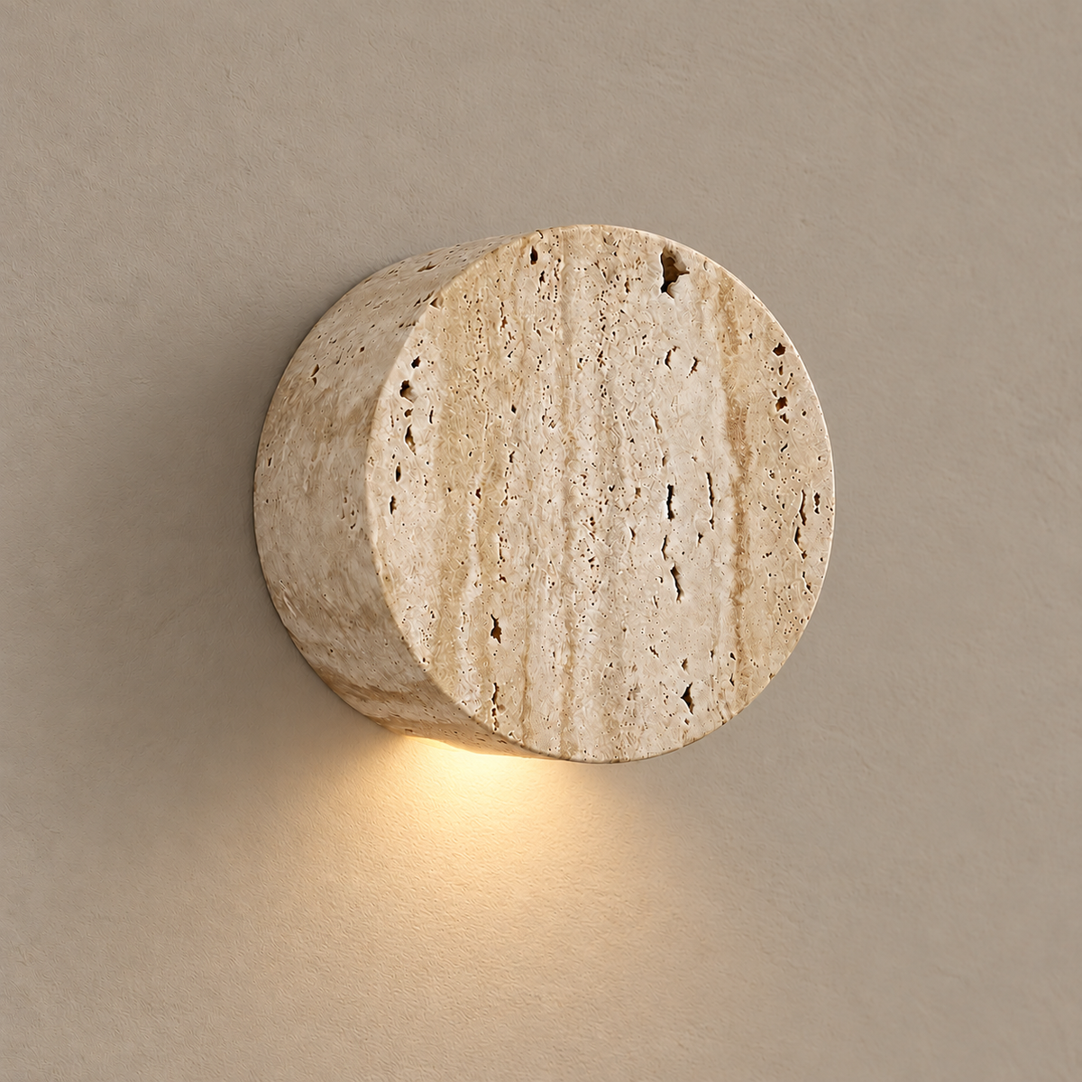 Bonetti travertine cylinder wall light, illuminated on a stone-beige wall