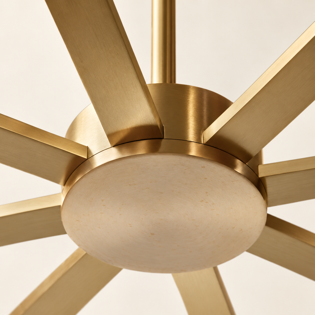 Underside of the CLDVY73 chandelier, showing its round brass cover and eight radial arms against warm ivory.