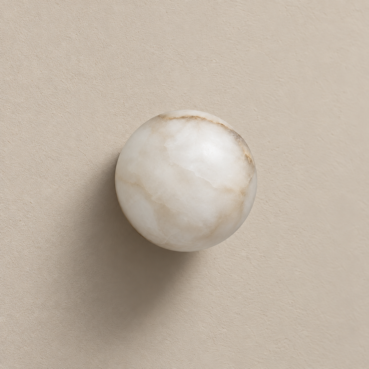 Front view of the unlit alabaster globe wall light against a warm beige wall.
