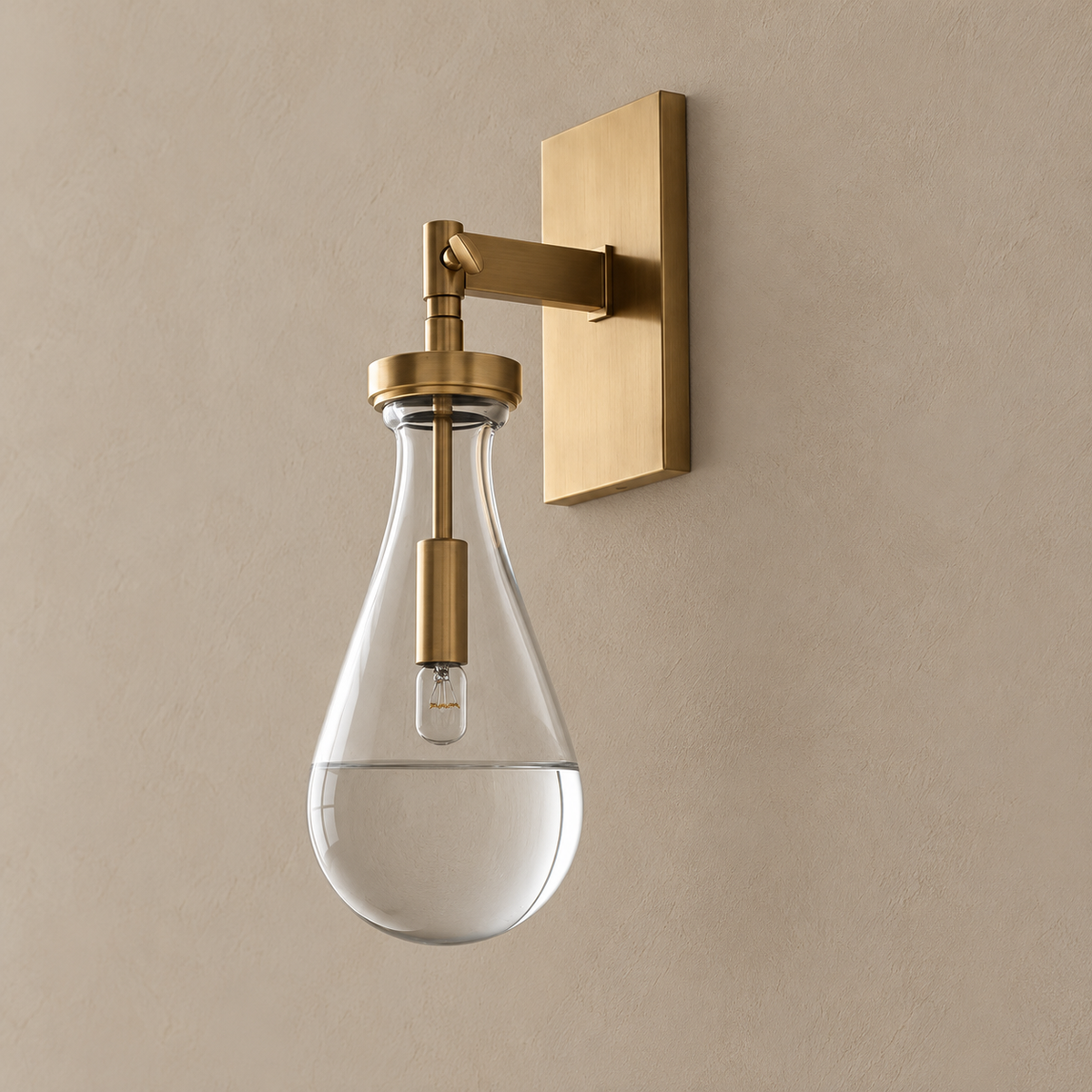 Raindrop glass wall sconce with brass backplate, shown unlit on a stone beige wall.