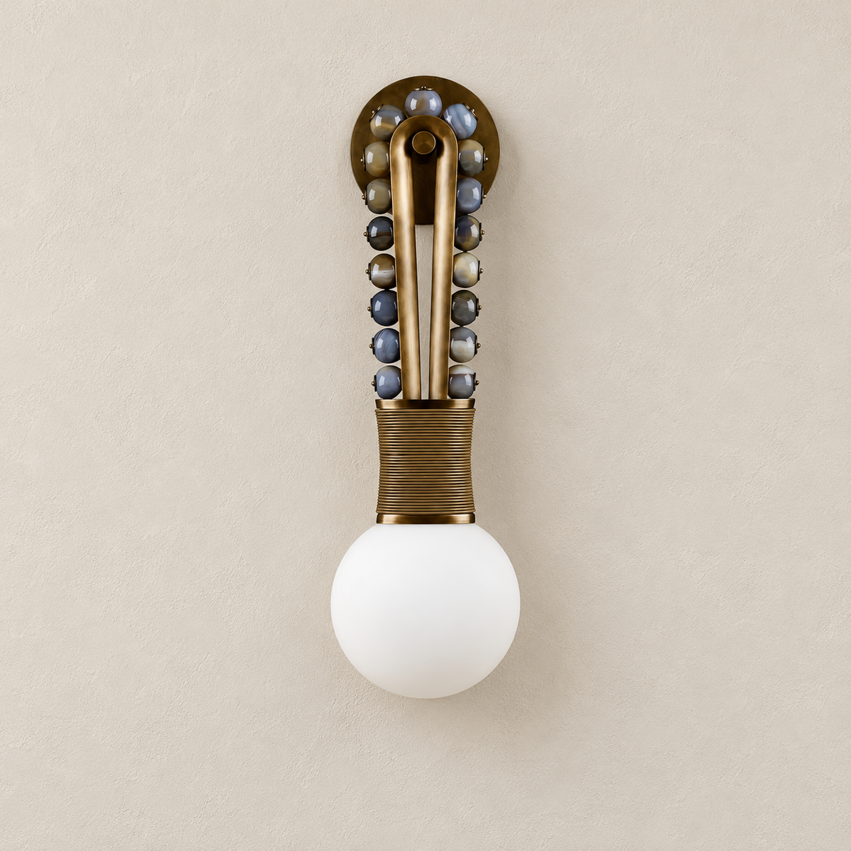 Patinated brass and jade-bead wall sconce with its white globe switched off.