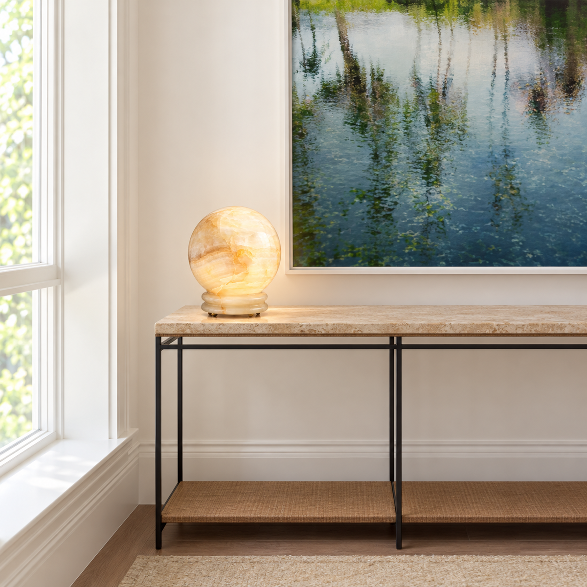 Onyx globe table lamp on a stone console beneath artwork
