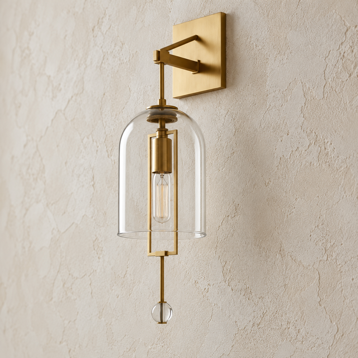 Oblique view of the brass and glass bell sconce mounted on a beige plaster wall.