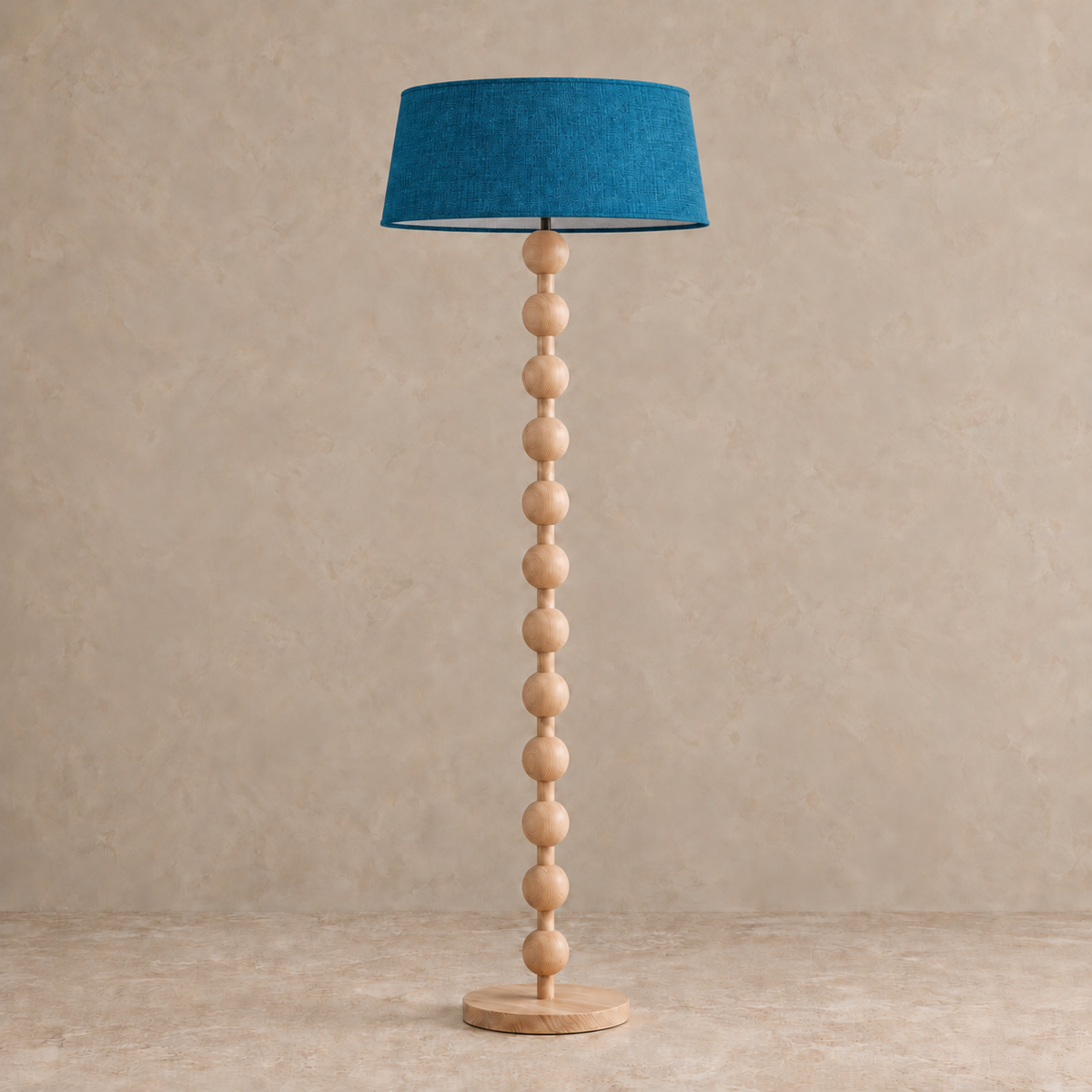 Sirmione Natural Wood Floor Lamp with petrol blue linen shade, unlit against a stone-beige background.