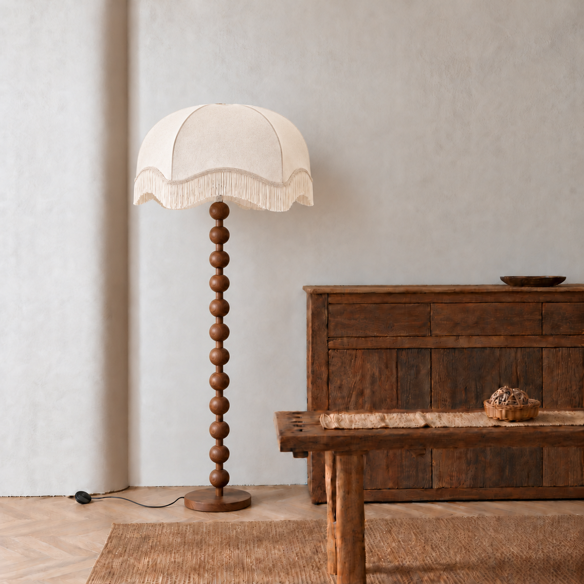 Sirmione walnut floor lamp with a broad cream fringe shade beside a wooden sideboard and bench.
