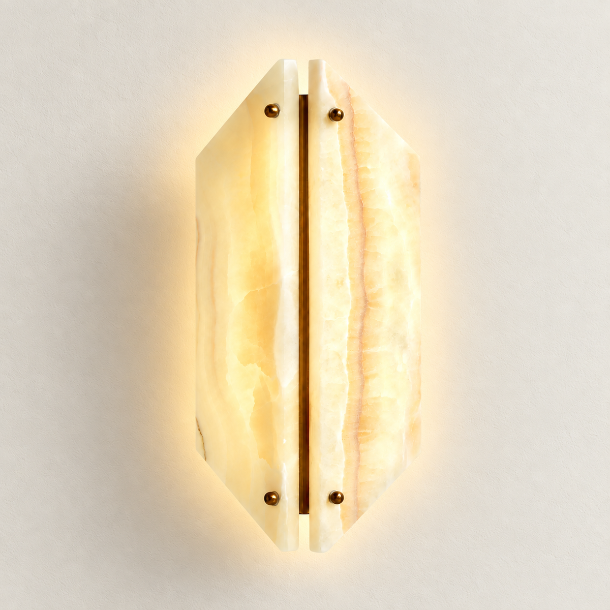 Geometric stone sconce illuminated, with light through its cream and honey veining.