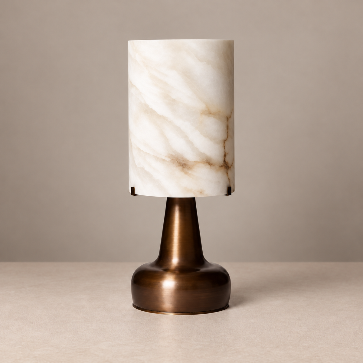 Alabaster cylinder table lamp with bronze pedestal, switched off on a beige background.