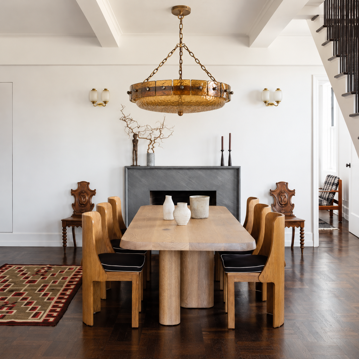 Amber glass bowl chandelier above a wooden dining table in a room with a charcoal fireplace.