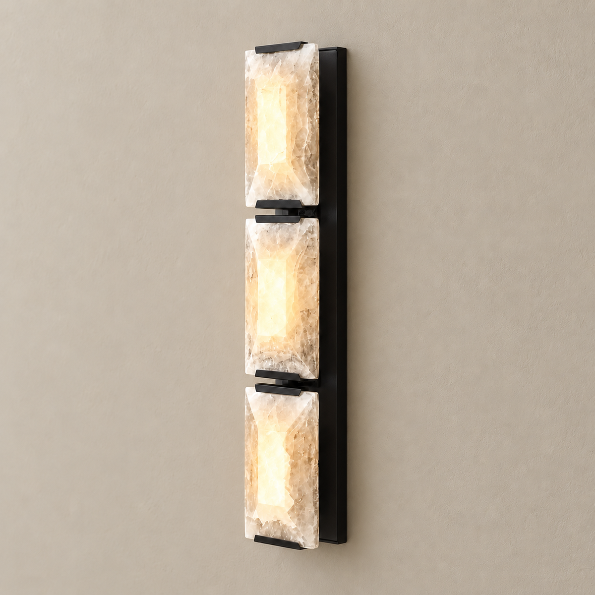 Triple calcite wall sconce with black hardware, illuminated through the natural stone.