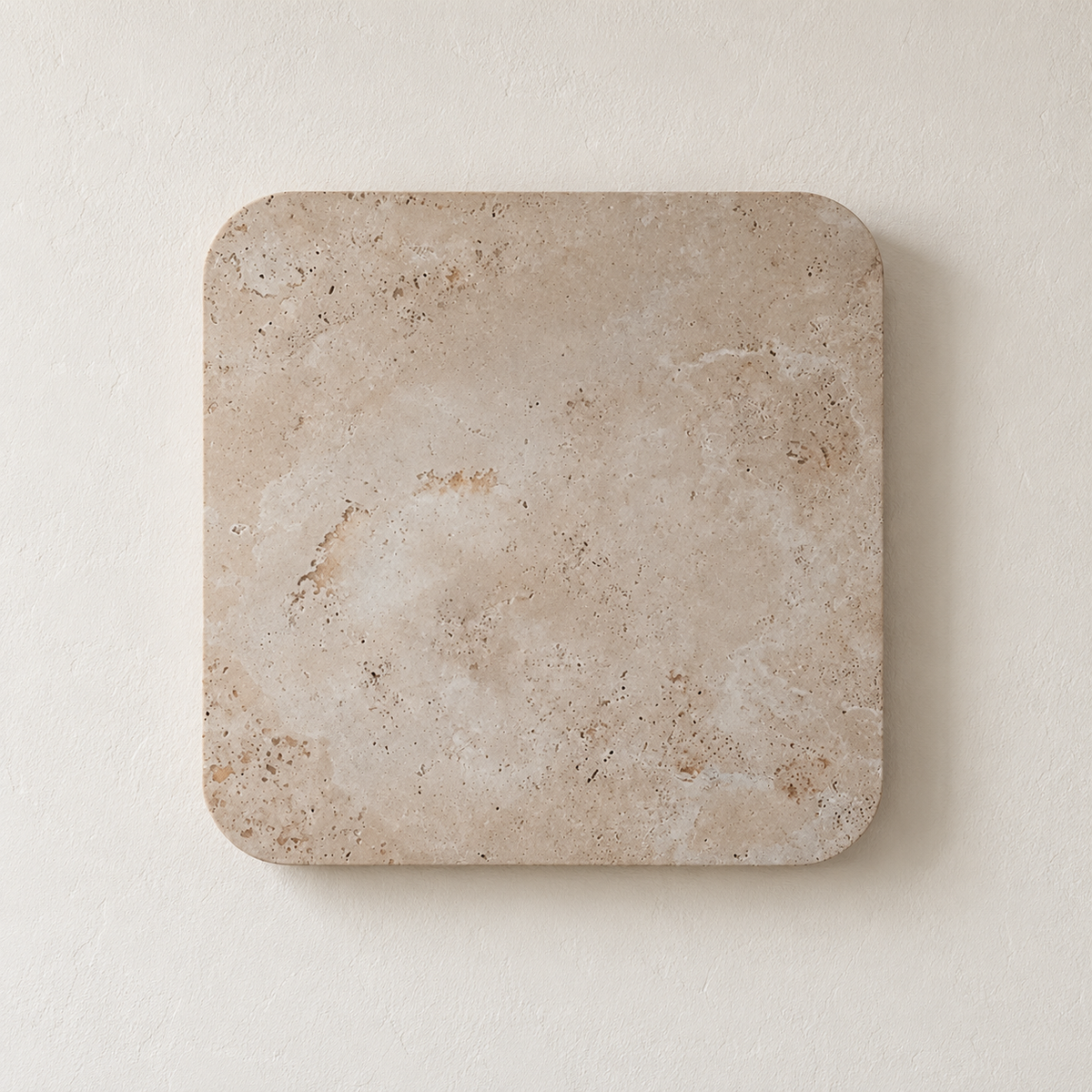 Square travertine wall light with rounded corners, switched off on ivory plaster.