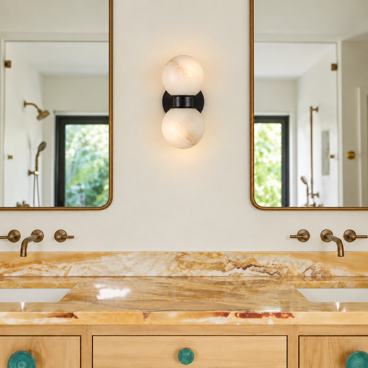 Double alabaster globe sconce mounted between brass-framed mirrors above a stone bathroom vanity.