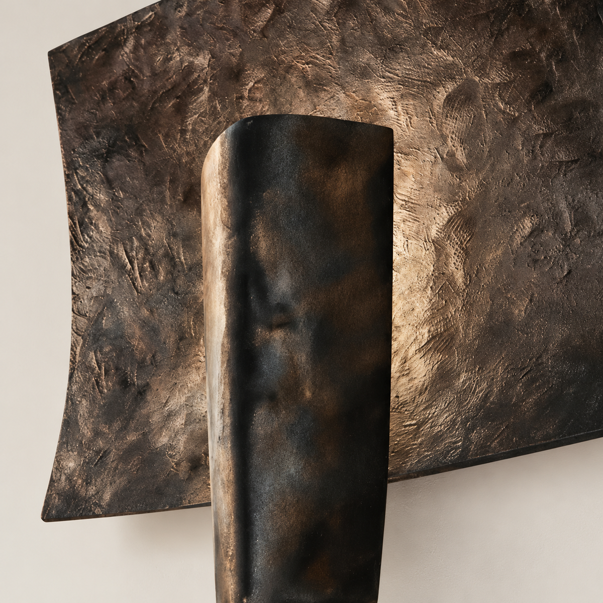 Close-up of the forged aluminium texture and dark patina on the Kyrin wall sconce.