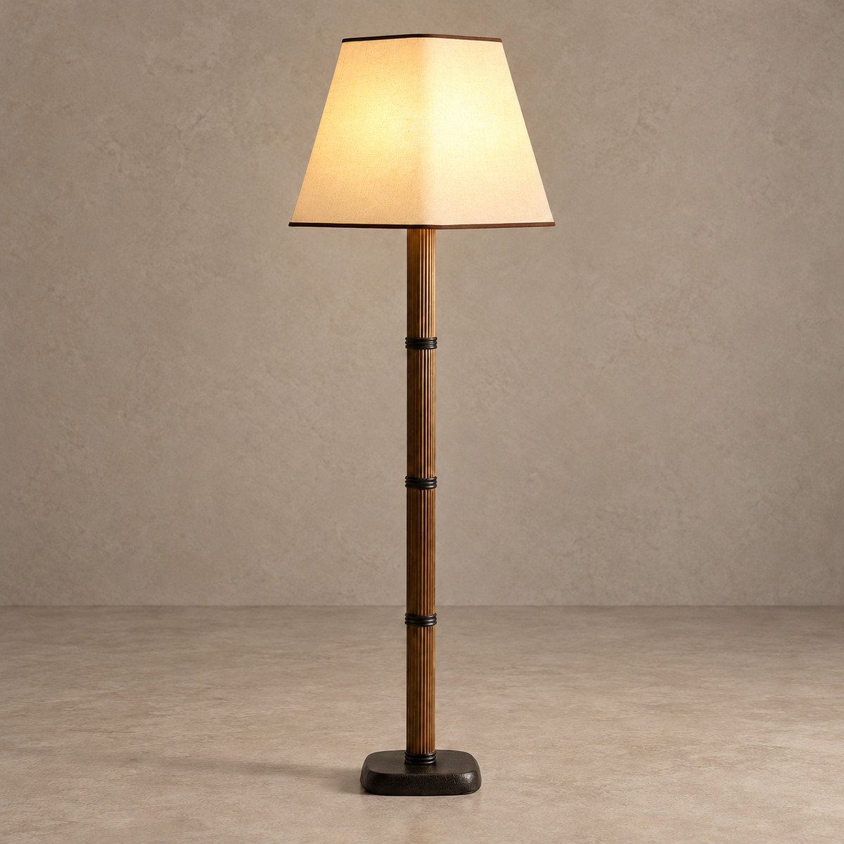 Galerie floor lamp with its cream linen shade illuminated above the bronzed fluted column.