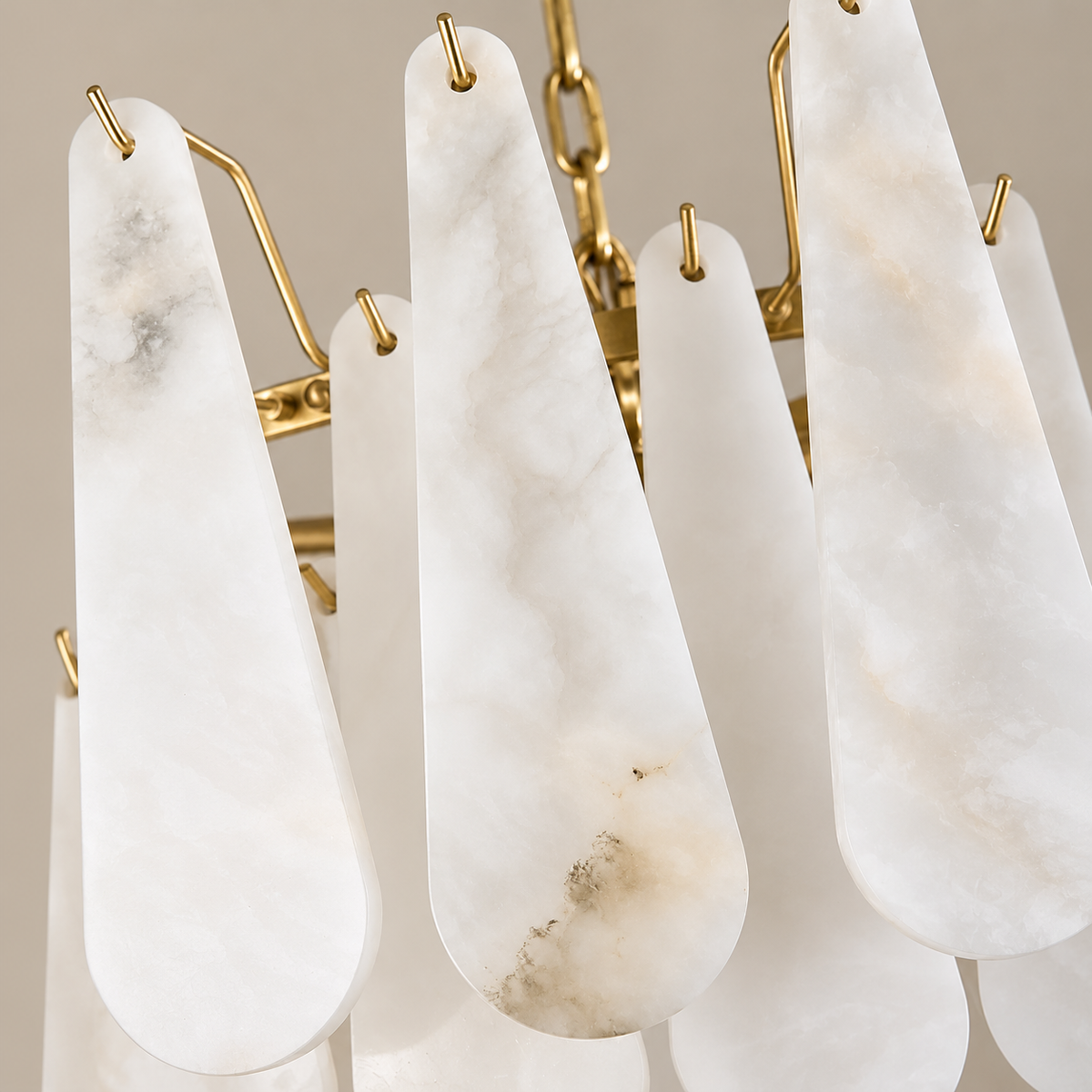Close view of Goccia alabaster teardrops showing cloudy layers, mineral inclusions and brass hooks.