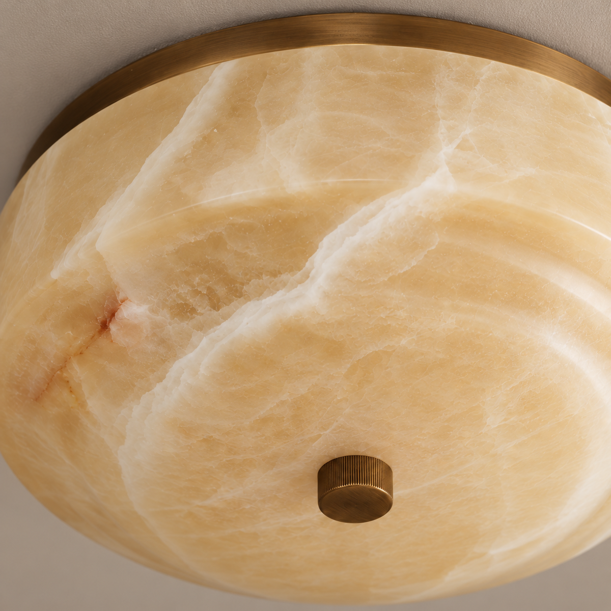 Close-up of honey onyx bands, the aged-brass rim and central finial.