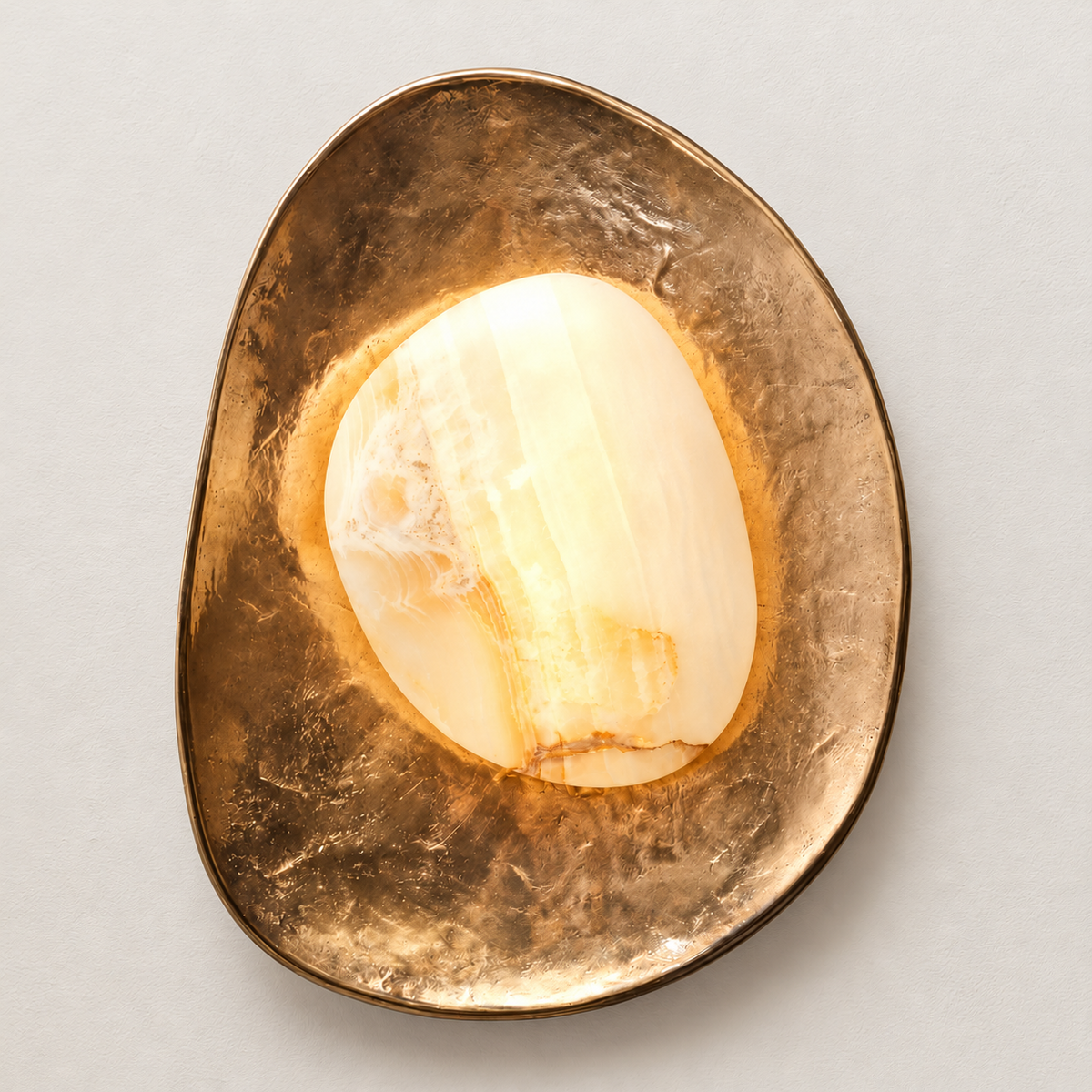 The same marble and brass wall sconce illuminated on ivory plaster.