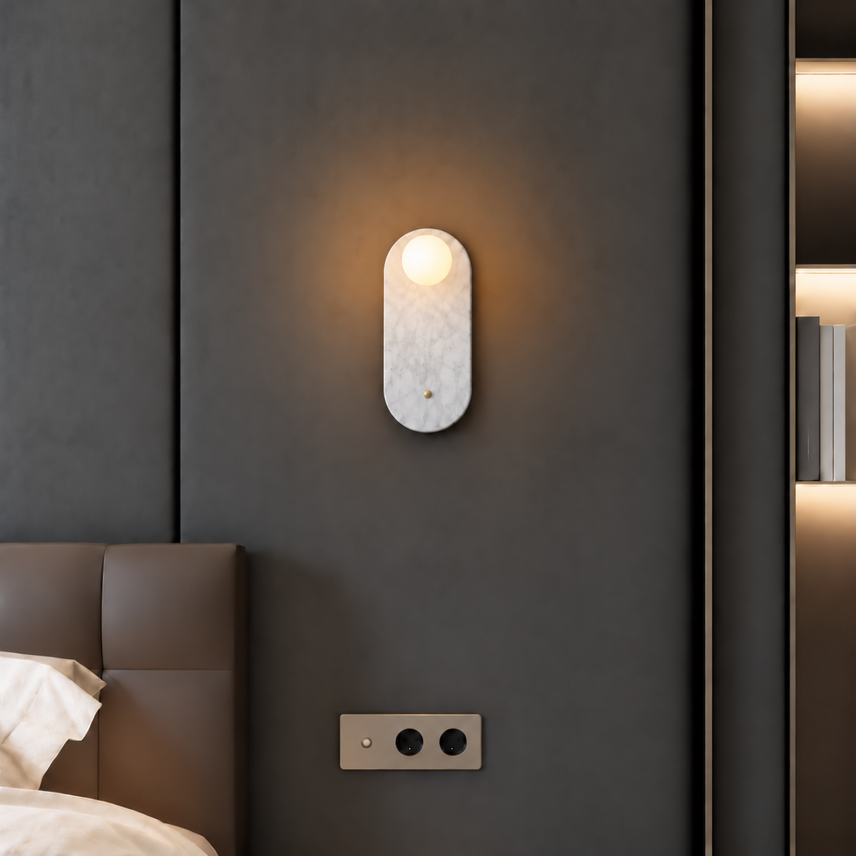 White marble wall sconce with a small frosted globe, mounted beside a bed.