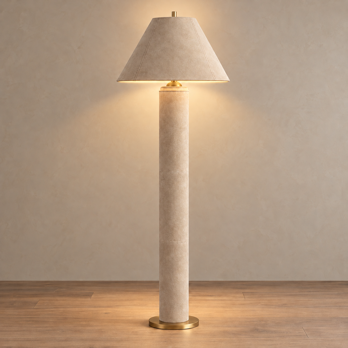 Montalcino beige leather floor lamp illuminated beneath its opaque stitched shade.