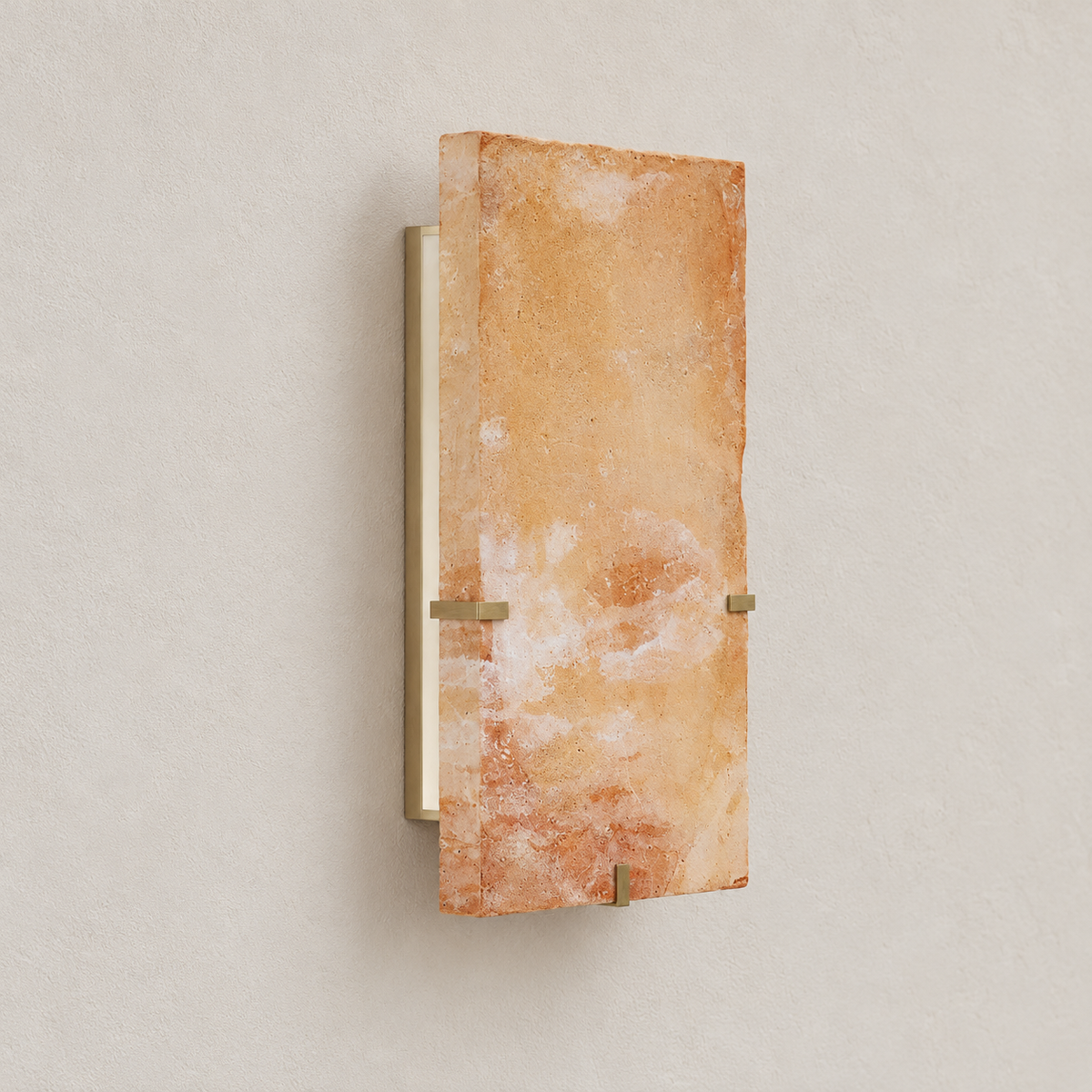 Angled view of the onyx wall sconce showing the stone slab, brass retaining clips and wall projection.