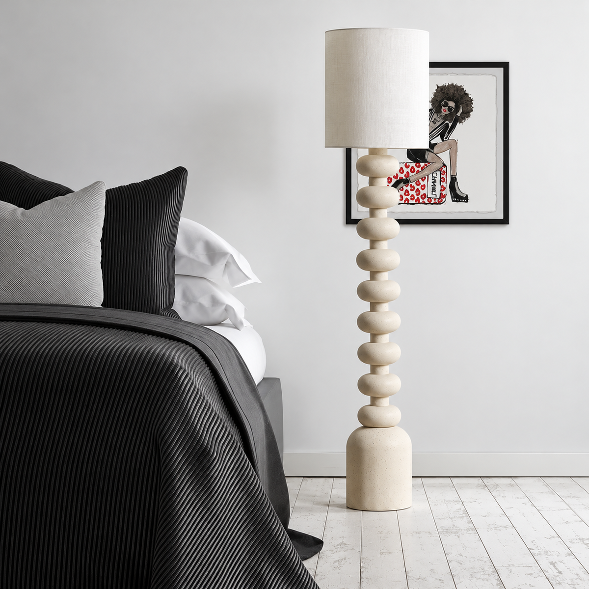 CL7774033 resin floor lamp beside a bed with black bedding and framed artwork.