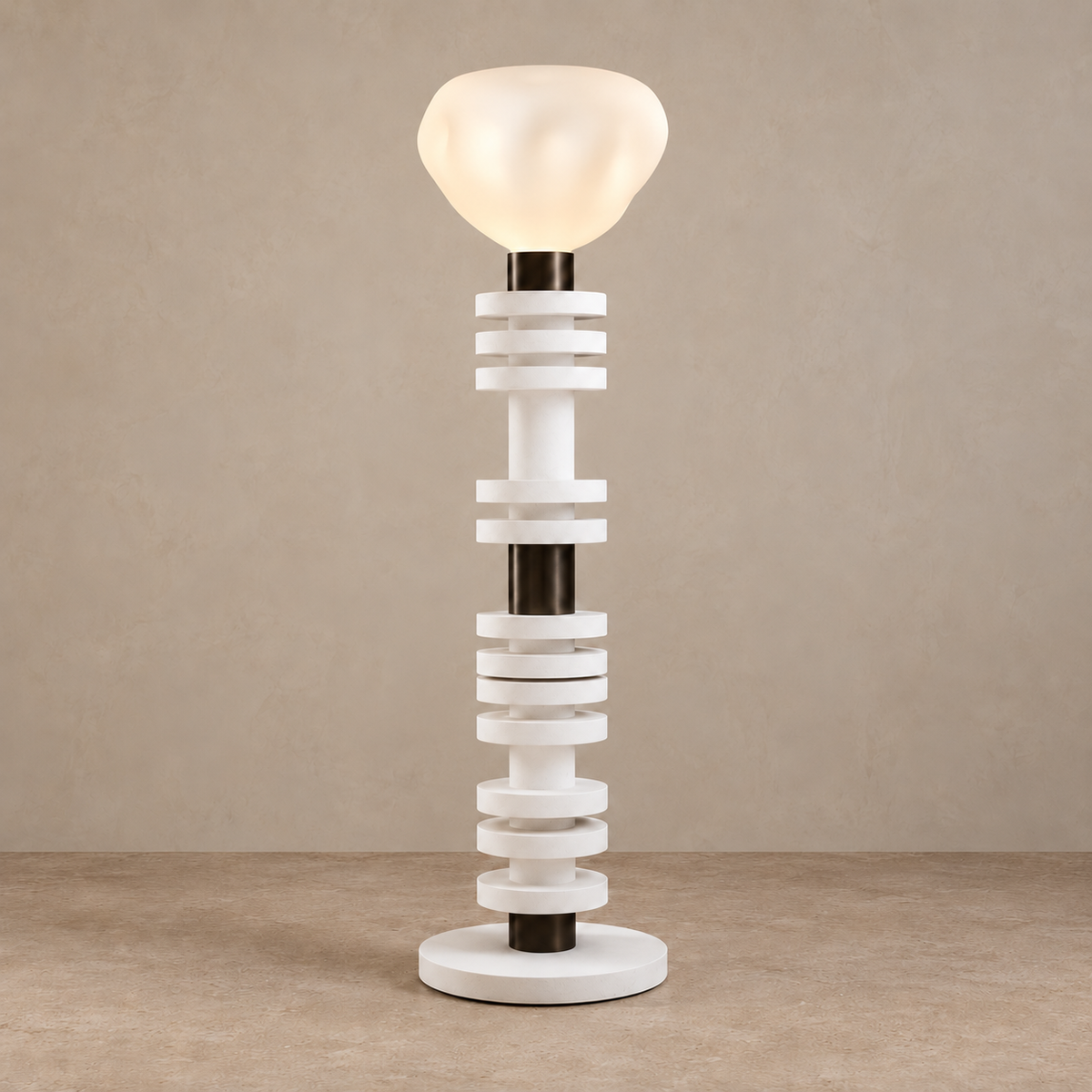 Stacking floor lamp with its softly dimpled white shade illuminated.