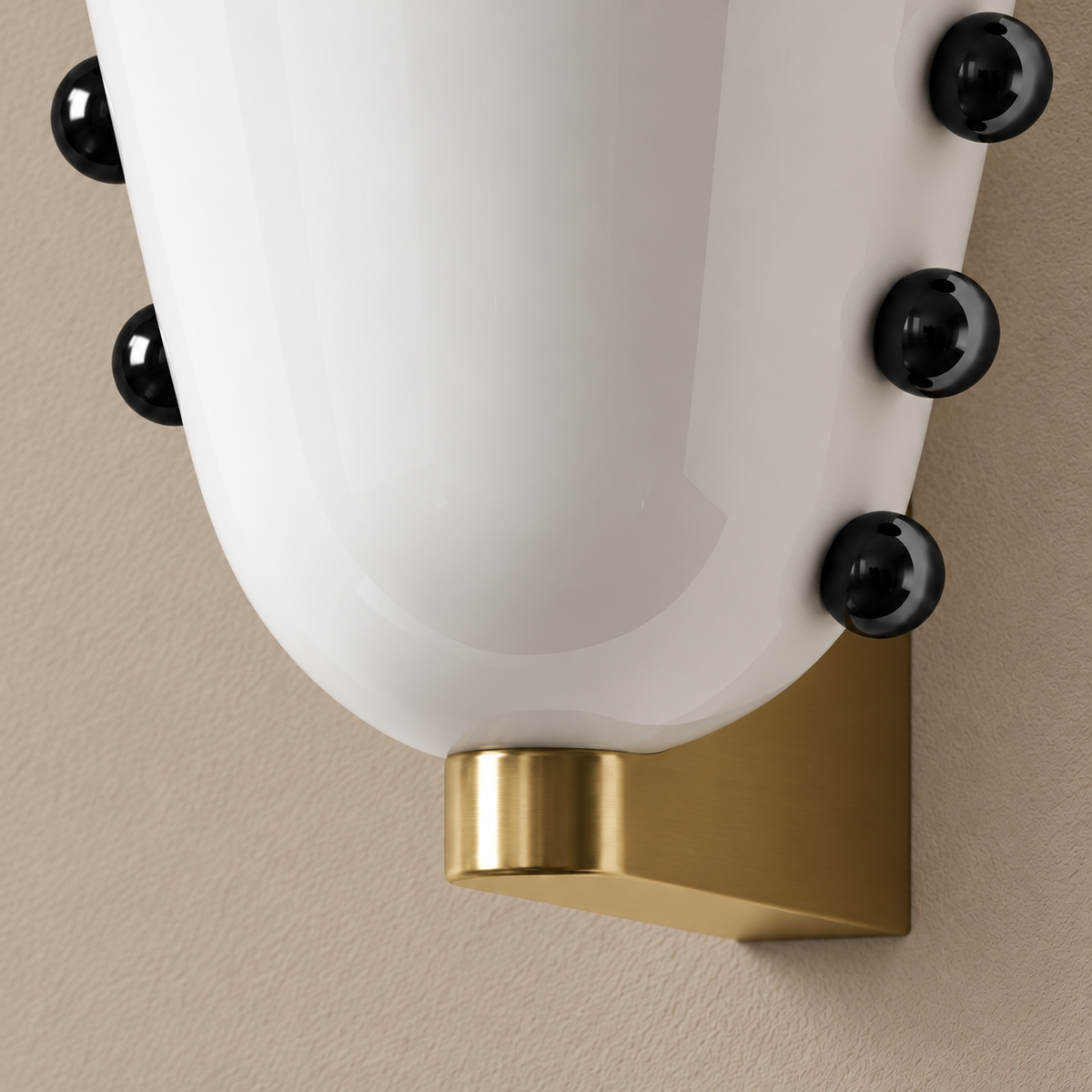 White glass wall sconce with black studs and gold brass mount, close view of the shade and brass support