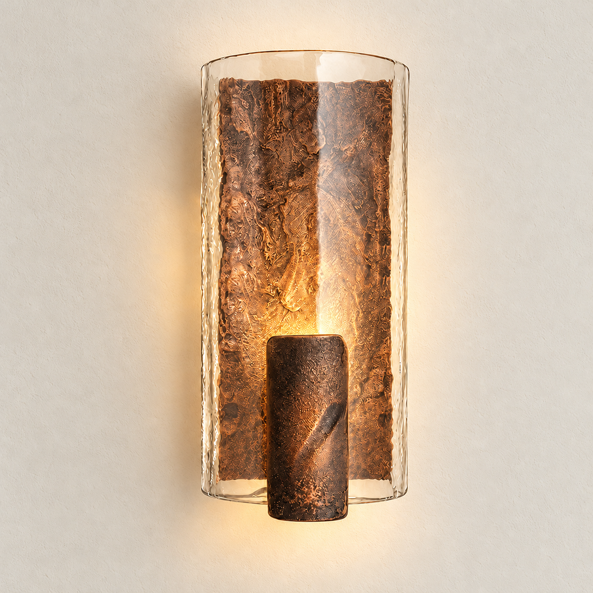 Copper-finish glass and cast-steel wall sconce illuminated with warm light, shown against warm ivory.