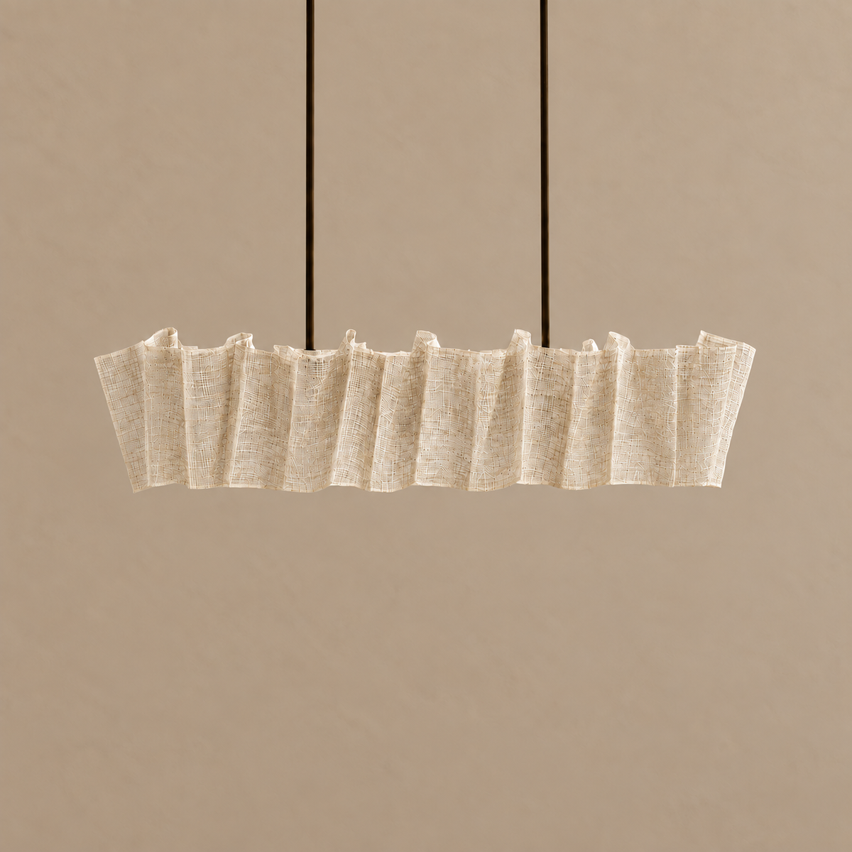 Sora linear abaca chandelier switched off, with a folded translucent shade and two black suspension cables.
