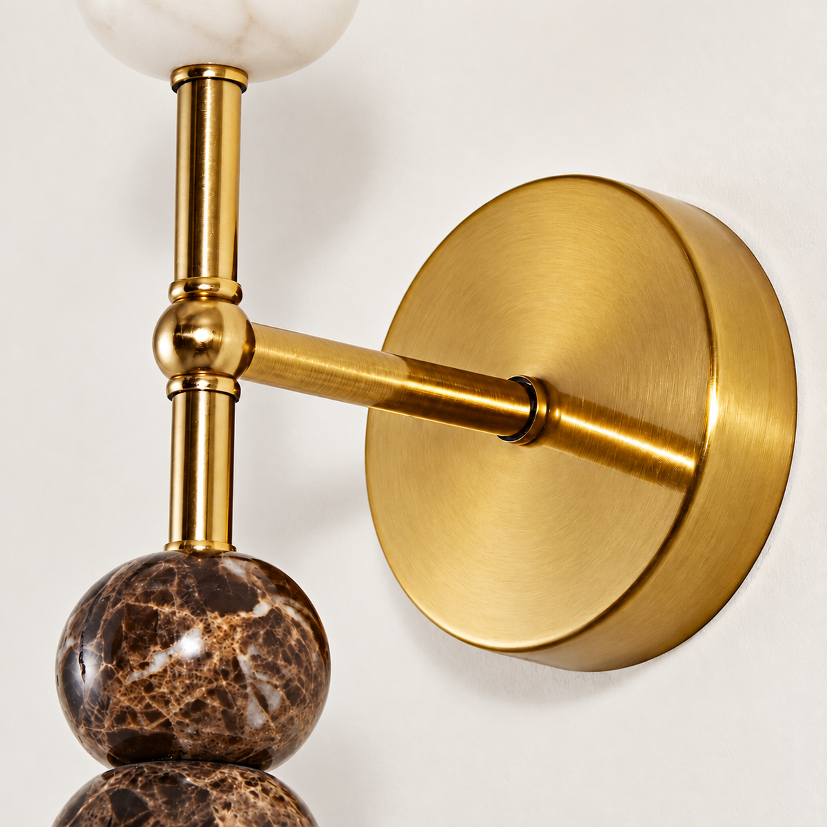 Close-up of the Totem Duetto sconce’s brass fittings and veined brown marble spheres.