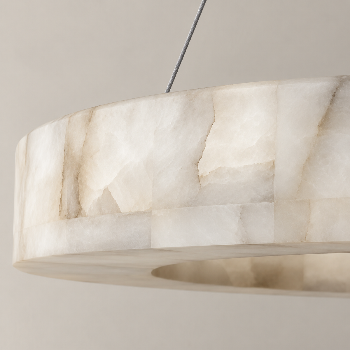 Close view of Triplo's alabaster ring showing cloudy mineral layers and its suspension cable.