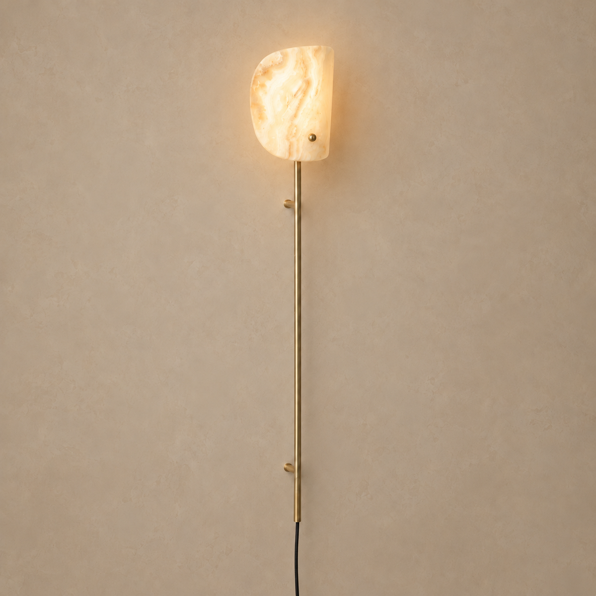 Valen onyx and brass wall rail lamp, illuminated on a stone-beige wall