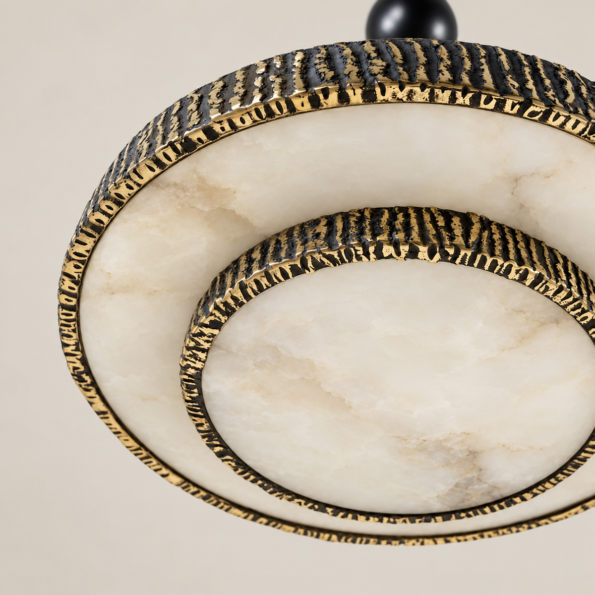 Natural cloudy alabaster diffusers bordered by bark-textured brass on the round chandelier.