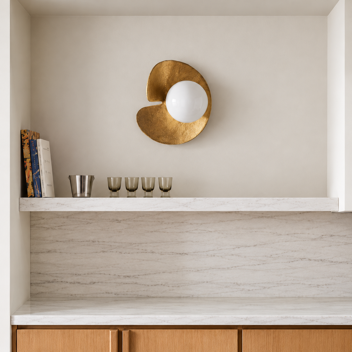 Aulia brass wall sconce above a marble backsplash and light oak kitchen cabinets.