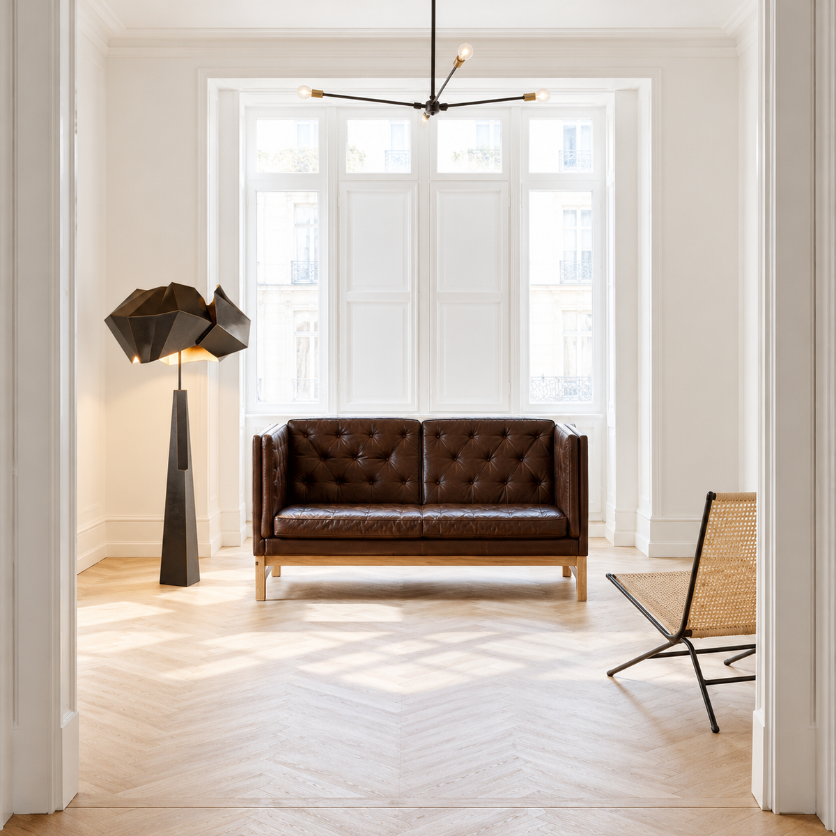 Black Aventine floor lamp beside a leather sofa in a daylit living room.