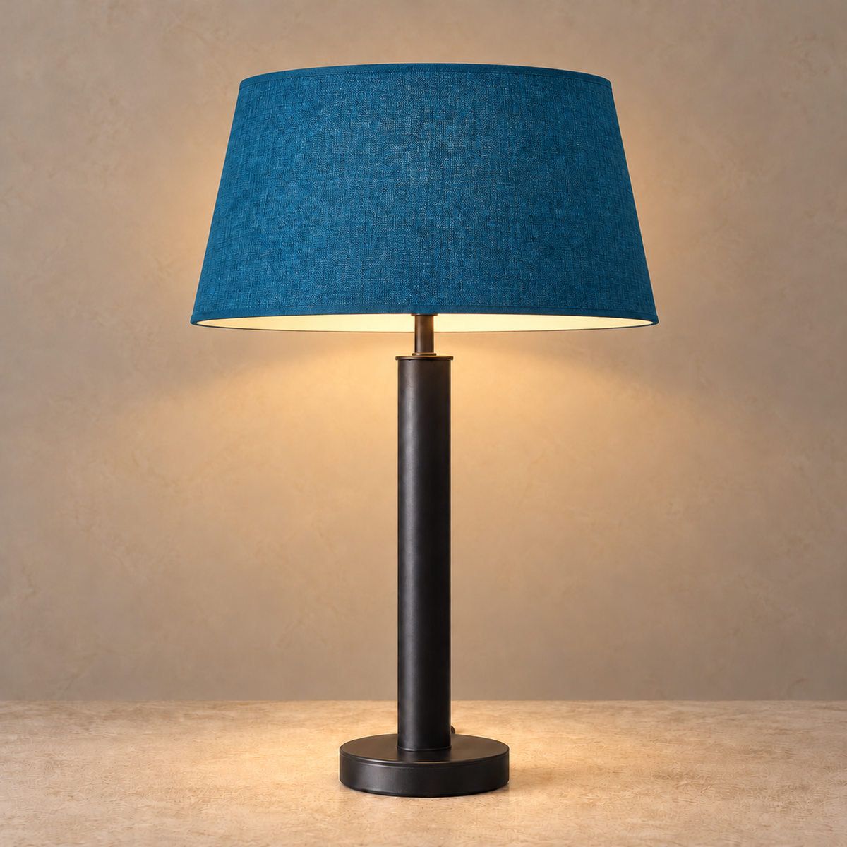 Matte black stainless steel table lamp illuminated beneath its petrol blue tapered fabric shade.