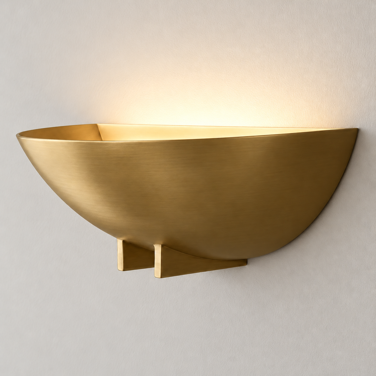 Brass bowl wall sconce casting warm uplight.
