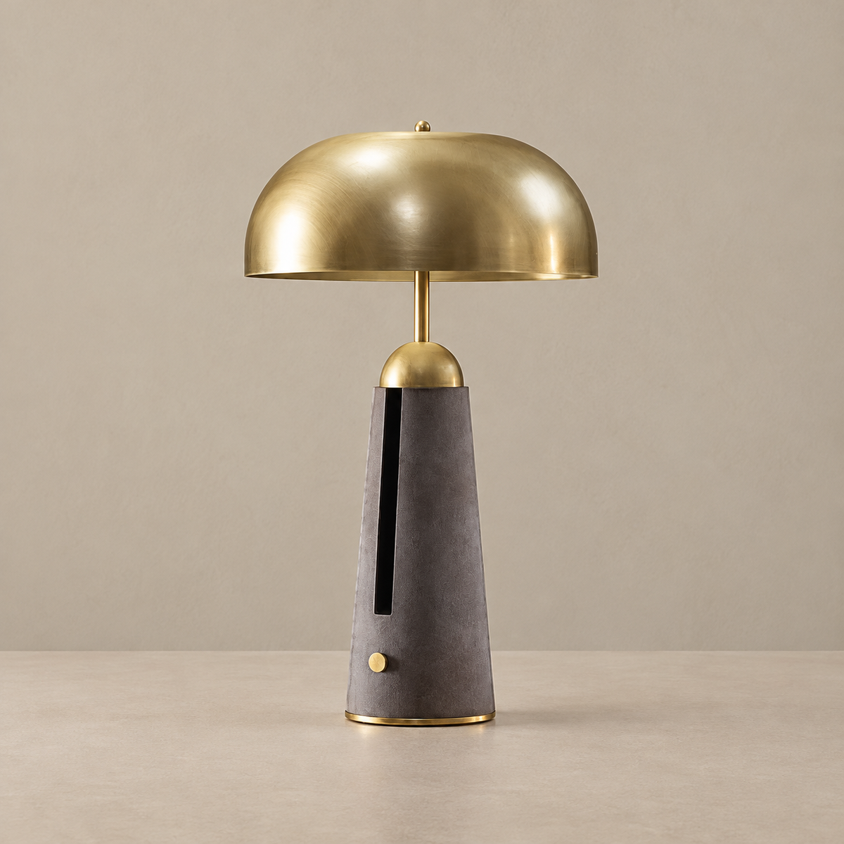 Brass dome table lamp with a charcoal leather base, unlit on a beige background