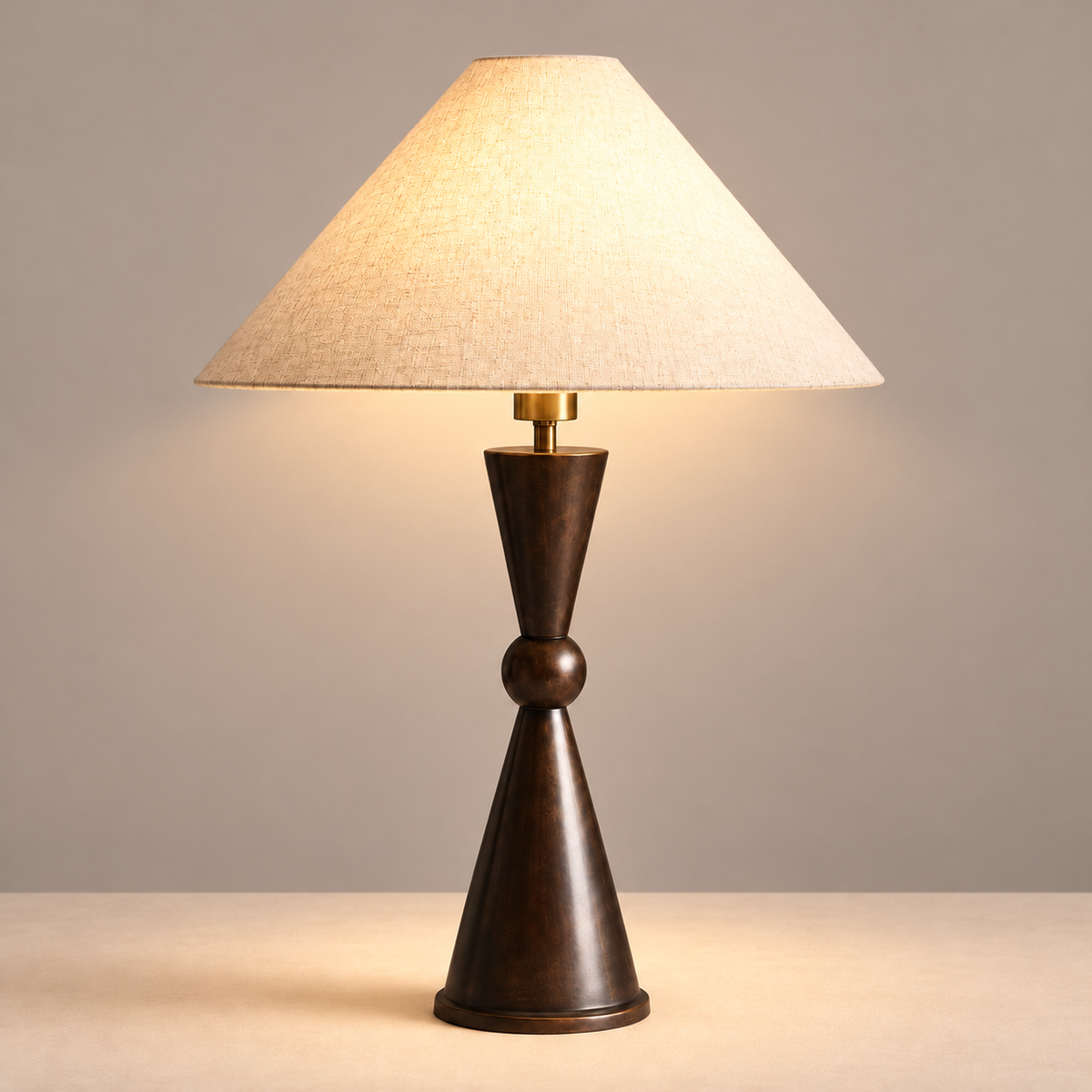 Geometric bronze table lamp with its linen shade illuminated