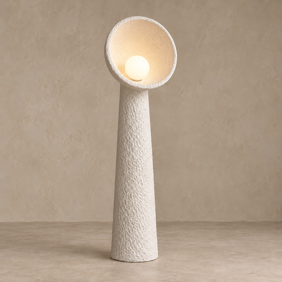 White plaster floor lamp with its globe bulb illuminating the textured bowl.